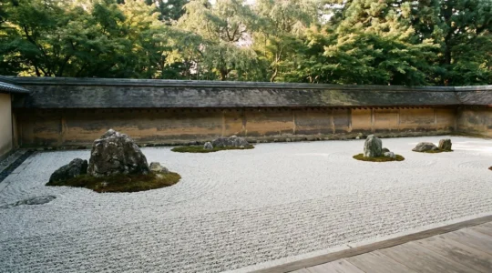 Vue panoramique d'un jardin de pierres zen japonais avec gravier ratissé et rochers disposés harmonieusement, invitant à la méditation